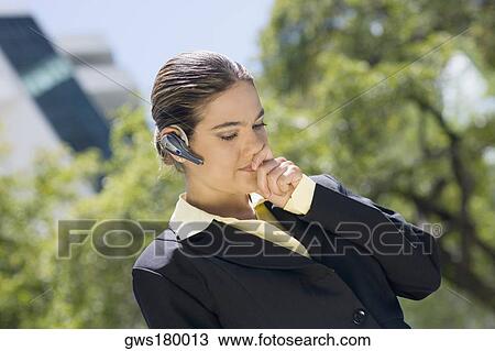 Businesswoman wearing a bluetooth device with her hands covering her mouth View Large Photo Image Stock Image - Businesswoman wearing a bluetooth device with her hands covering her mouth. Fotosearch