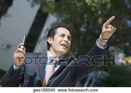 Close-up of a businessman holding a mobile phone and pointing upwards View Large Photo Image Stock Image - Close-up of a businessman holding a mobile phone and pointing upwards. Fotosearch