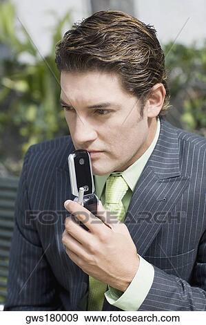 Stock Photo - Close-up of a businessman holding a mobile phone and thinking. Fotosearch