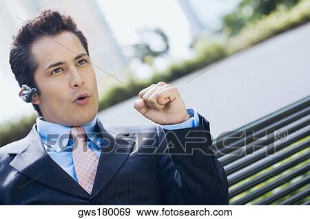 Stock Photo - Close-up of a businessman wearing a bluetooth device and making a fist. Fotosearch
