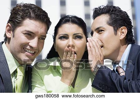 Stock Photo - Close-up of a businesswoman gossiping with two businesswomen. Fotosearch