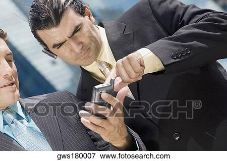 Close-up of two businessmen using a palmtop View Large Photo Image Stock Photo - Close-up of two businessmen using a palmtop. Fotosearch