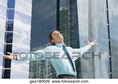 Stock Photograph - Low angle view of a businessman standing with his arms outstretched. Fotosearch