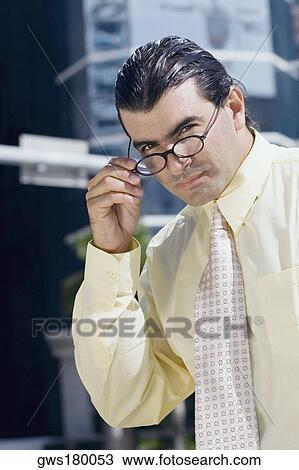 Portrait of a businessman adjusting his eyeglasses View Large Photo Image Stock Image - Portrait of a businessman adjusting his eyeglasses. Fotosearch