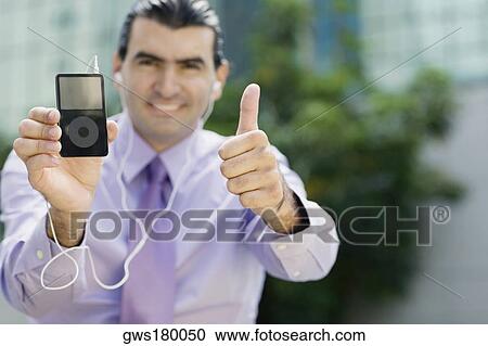 Stock Image - Portrait of a businessman showing an MP3 player and making a thumbs up sign. Fotosearch