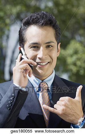 Stock Photography - Portrait of a businessman talking on a mobile phone and showing call me gesture. Fotosearch