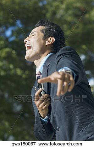 Stock Photo - Side profile of a businessman holding a mobile phone and laughing. Fotosearch