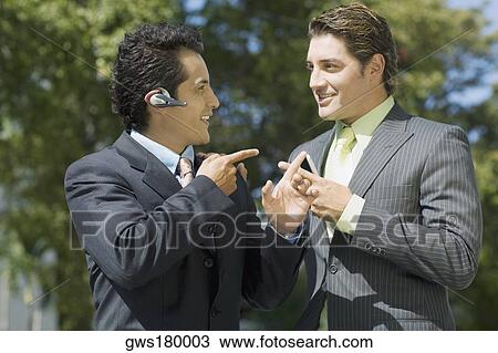 Stock Image - Two businessmen looking at each other and smiling. Fotosearch