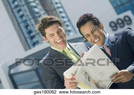 Stock Image - Two businessmen reading a magazine and smiling. Fotosearch