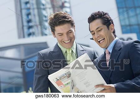Stock Image - Two businessmen reading a magazine and smiling. Fotosearch