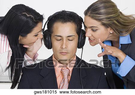 Close-up of a businessman listening to music while two businesswomen bothering him View Large Photo Image Stock Photography - Close-up of a businessman listening to music while two businesswomen bothering him. Fotosearch