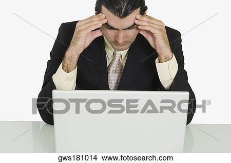 Close-up of a businessman sitting in front of a laptop with his head in his hands View Large Photo Image Picture - Close-up of a businessman sitting in front of a laptop with his head in his hands. Fotosearch