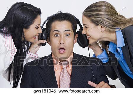 Close-up of two businesswomen pulling headphones of a businessman View Large Photo Image Stock Photography - Close-up of two businesswomen pulling headphones of a businessman. Fotosearch