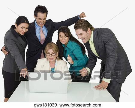 Stock Photo - Four business executives surrounding a businesswoman working on a laptop. Fotosearch