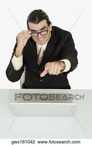 Portrait of a businessman adjusting his eyeglasses and pointing forward View Large Photo Image Stock Image - Portrait of a businessman adjusting his eyeglasses and pointing forward. Fotosearch