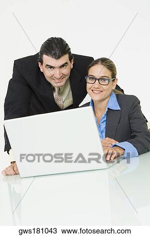 Portrait of a businessman and a businesswoman smiling in front of a laptop View Large Photo Image Stock Image - Portrait of a businessman and a businesswoman smiling in front of a laptop. Fotosearch