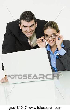 Portrait of a businessman and a businesswoman smiling in front of a laptop View Large Photo Image Stock Photo - Portrait of a businessman and a businesswoman smiling in front of a laptop. Fotosearch