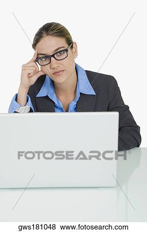 Portrait of a businessman sitting in front of a laptop and thinking View Large Photo Image Stock Photo - Portrait of a businessman sitting in front of a laptop and thinking. Fotosearch