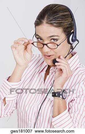 Stock Photo - Portrait of a businesswoman adjusting her eyeglasses and a headset. Fotosearch