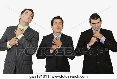 Stock Image - Portrait of three businessmen adjusting their ties. Fotosearch