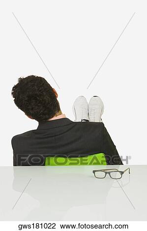Rear view of a businessman sitting with his feet up in an office View Large Photo Image Stock Image - Rear view of a businessman sitting with his feet up in an office. Fotosearch