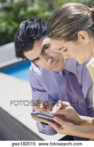 Stock Photography - Businessman and a businesswoman operating a mobile phone. Fotosearch