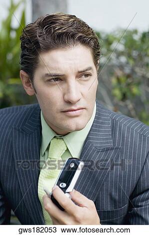 Close-up of a businessman holding a mobile phone View Large Photo Image Stock Image - Close-up of a businessman holding a mobile phone. Fotosearch