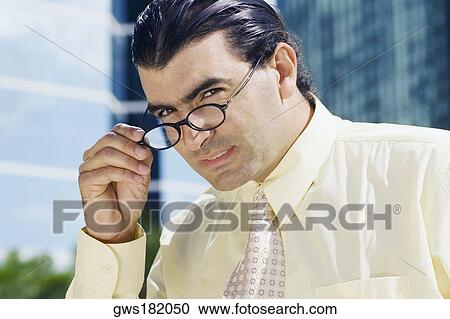 Portrait of a businessman peeking over his eyeglasses View Large Photo Image Stock Image - Portrait of a businessman peeking over his eyeglasses. Fotosearch