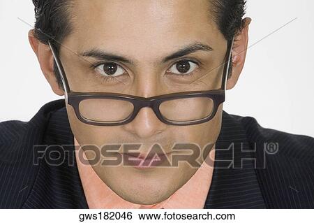 Portrait of a businessman peeking over his eyeglasses View Large Photo Image Stock Photograph - Portrait of a businessman peeking over his eyeglasses. Fotosearch