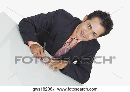Stock Photo - Portrait of a businessman writing on a sheet of paper and smiling. Fotosearch