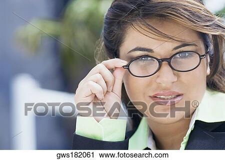 Stock Image - Portrait of a businesswoman adjusting her eyeglasses. Fotosearch