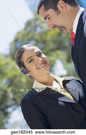 Stock Photography - Portrait of a businesswoman wearing a hands free device with a businessman smiling beside her. Fotosearch