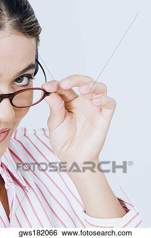 Portrait of a young woman peeking over her eyeglasses View Large Photo Image Stock Photograph - Portrait of a young woman peeking over her eyeglasses. Fotosearch