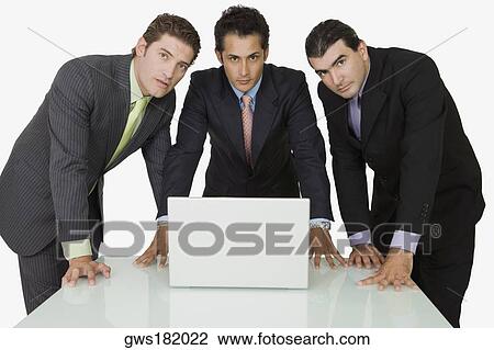 Stock Image - Portrait of three businessmen in front of a laptop. Fotosearch