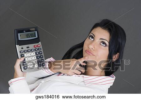 Close-up of a businesswoman holding a calculator and contemplating View Large Photo Image Stock Photograph - Close-up of a businesswoman holding a calculator and contemplating. Fotosearch