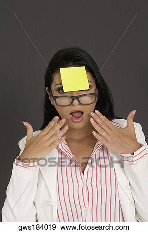 Close-up of a businesswoman looking shocked with an adhesive note in front of her forehead View Large Photo Image Stock Photo - Close-up of a businesswoman looking shocked with an adhesive note in front of her forehead. Fotosearch
