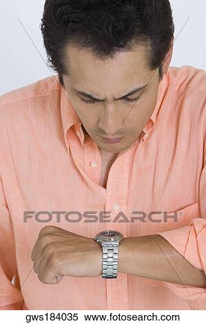 Stock Photography - Close-up of a young man looking at his watch. Fotosearch