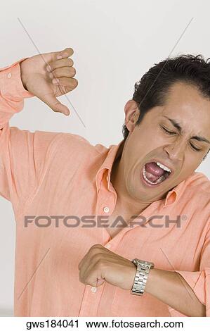 Close-up of a young man yawning after checking the time on his wristwatch View Large Photo Image Stock Image - Close-up of a young man yawning after checking the time on his wristwatch. Fotosearch