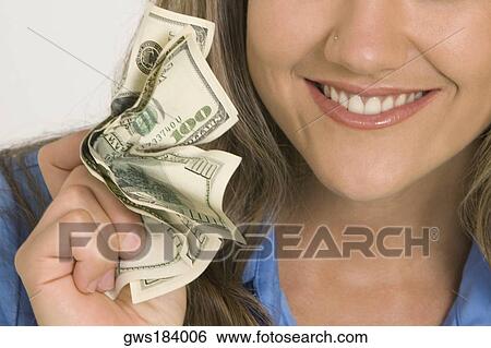 Close-up of a young woman holding American paper currency and smiling View Large Photo Image Stock Photograph - Close-up of a young woman holding American paper currency and smiling. Fotosearch