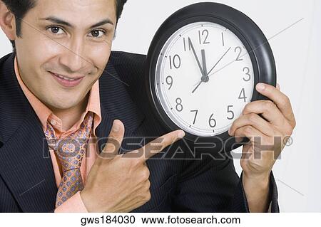Portrait of a businessman pointing at a clock View Large Photo Image Stock Image - Portrait of a businessman pointing at a clock. Fotosearch