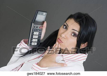 Portrait of a businesswoman holding a calculator and making a face View Large Photo Image Stock Photo - Portrait of a businesswoman holding a calculator and making a face. Fotosearch