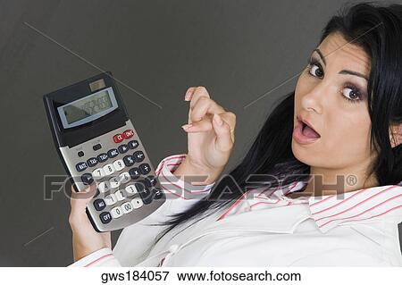 Stock Photo - Portrait of a businesswoman holding a calculator and pointing at it. Fotosearch