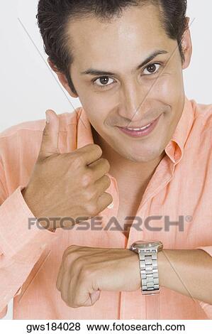 Portrait of a young man giving thumbs up after checking the time on his wristwatch View Large Photo Image Stock Photo - Portrait of a young man giving thumbs up after checking the time on his wristwatch. Fotosearch