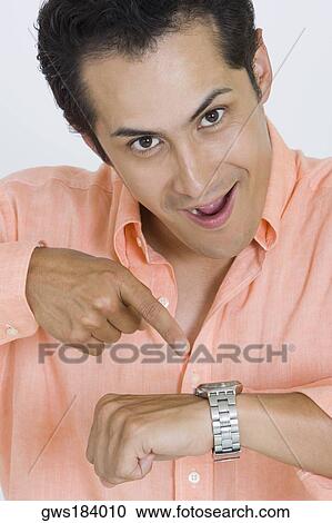 Portrait of a young man pointing at his wristwatch View Large Photo Image Stock Image - Portrait of a young man pointing at his wristwatch. Fotosearch