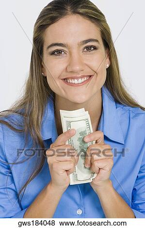 Portrait of a young woman holding American paper currency and smiling View Large Photo Image Stock Photo - Portrait of a young woman holding American paper currency and smiling. Fotosearch