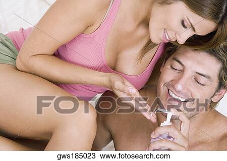Stock Image - Close-up of a mid adult man putting lotion on a young woman's hand and smiling. Fotosearch