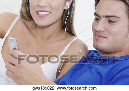 Stock Image - Close-up of a young couple listening to an MP3 player. Fotosearch