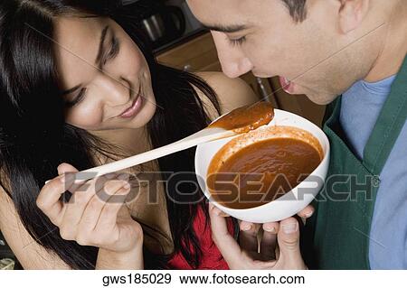 Close-up of a young woman feeding tomato soup to a mid adult man in the kitchen View Large Photo Image Stock Photo - Close-up of a young woman feeding tomato soup to a mid adult man in the kitchen. Fotosearch