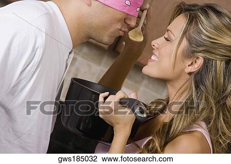 Stock Image - Close-up of a young woman making a blindfolded mid adult man to taste food. Fotosearch