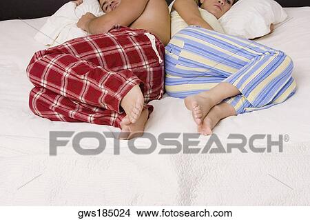 Picture - High angle view of a young couple lying back to back on the bed. Fotosearch